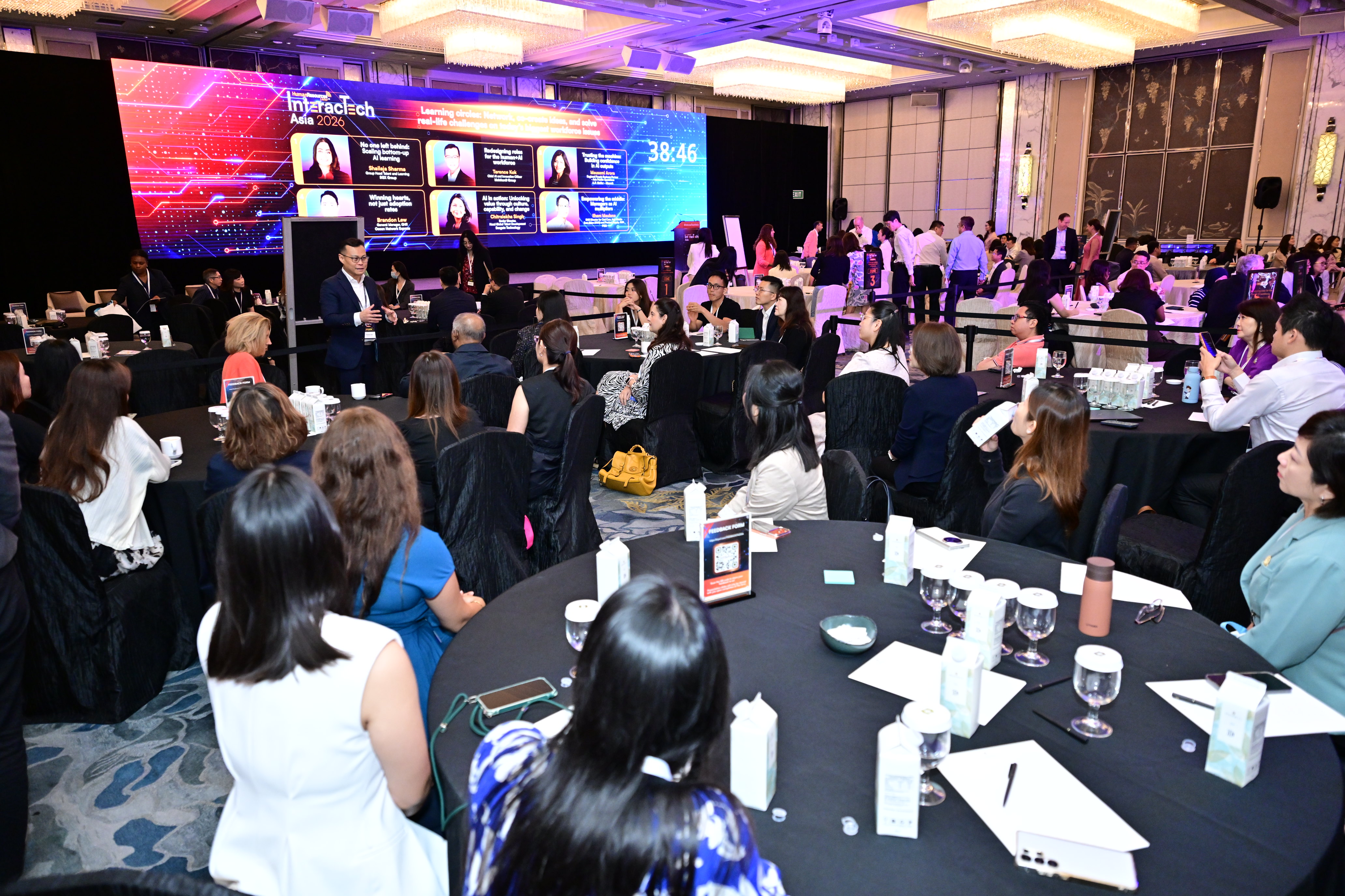 Terence Kok moderating AI in HR session at InteracTech Asia 2026 — full ballroom audience with event branding on screen